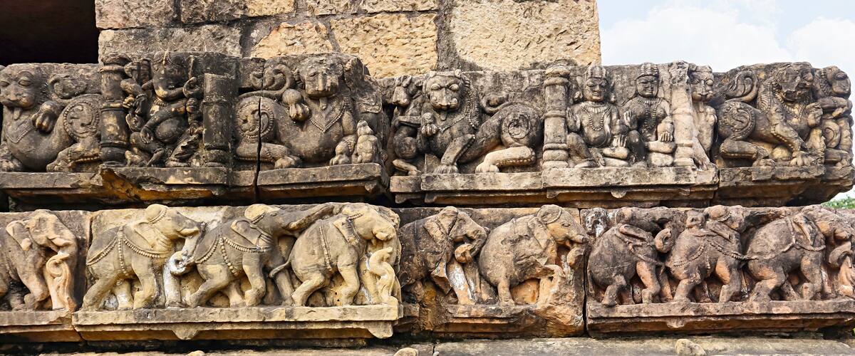 Detailed stone carvings of mythological figures and animals on a temple wall.