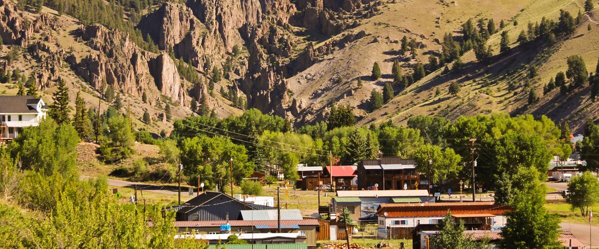 A mountainous landscape with a small town nestled at its base, featuring rugged cliffs and sparse vegetation.