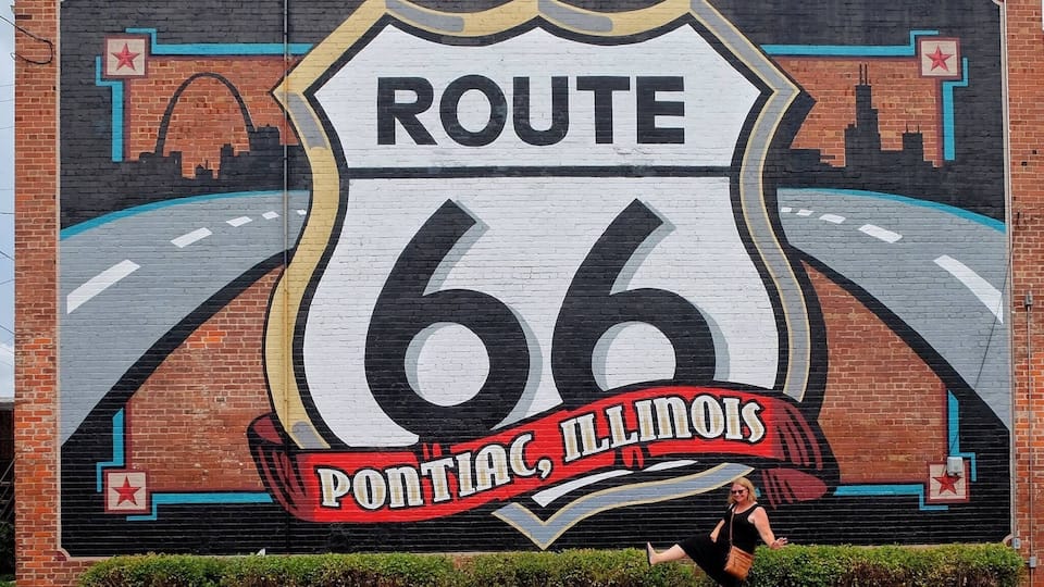 A mural of Route 66 with the text 'PONTIAC, ILLINOIS' on a brick wall.