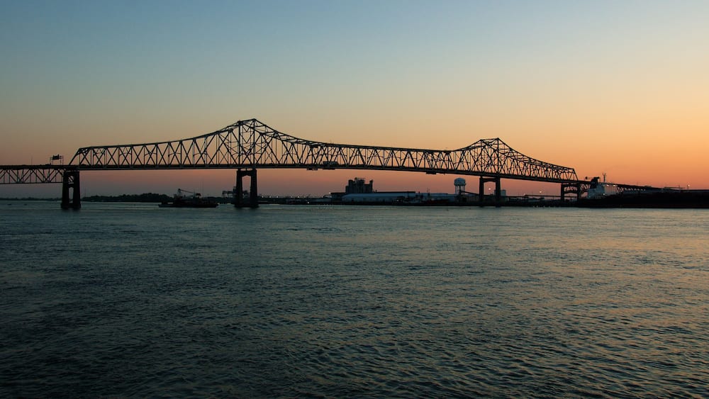 Un pont enjambant une étendue d’eau, avec un coucher de soleil en arrière-plan.