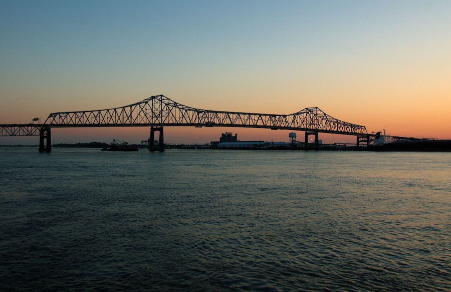 Un puente que cruza un cuerpo de agua, con un atardecer de fondo.