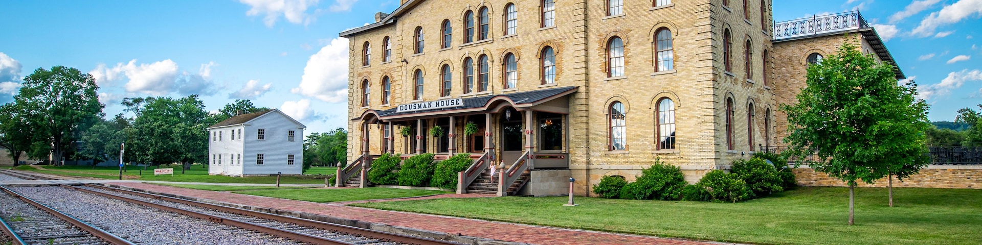 Un edificio histórico con un cartel que dice 'DOUSMAN HOUSE' frente a una vía de tren.