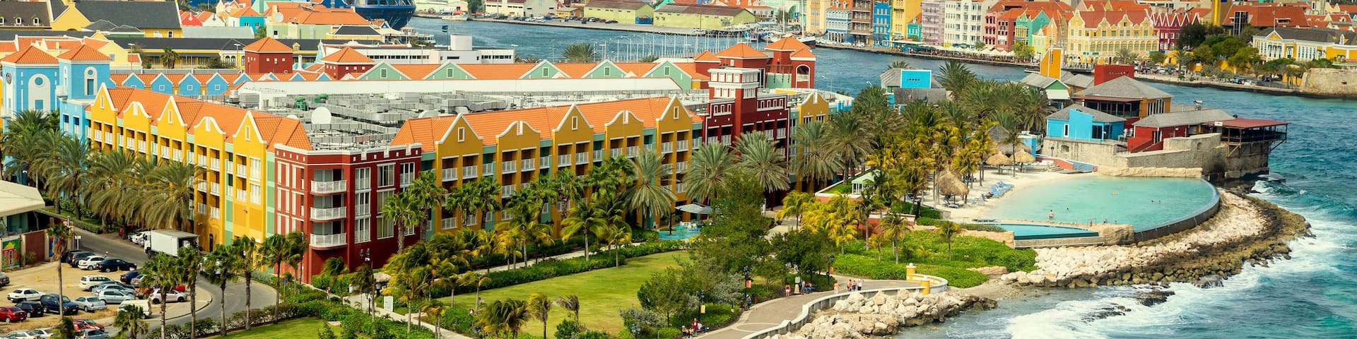 A coastal resort with colorful buildings, a beach, and a rocky shoreline.