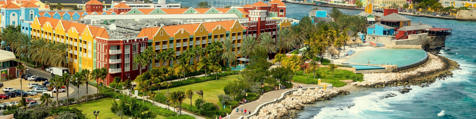 Um resort costeiro com edifícios coloridos, uma praia e um litoral rochoso.