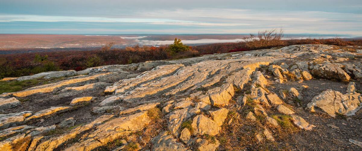 A rocky terrain with autumn foliage and distant views of a valley.