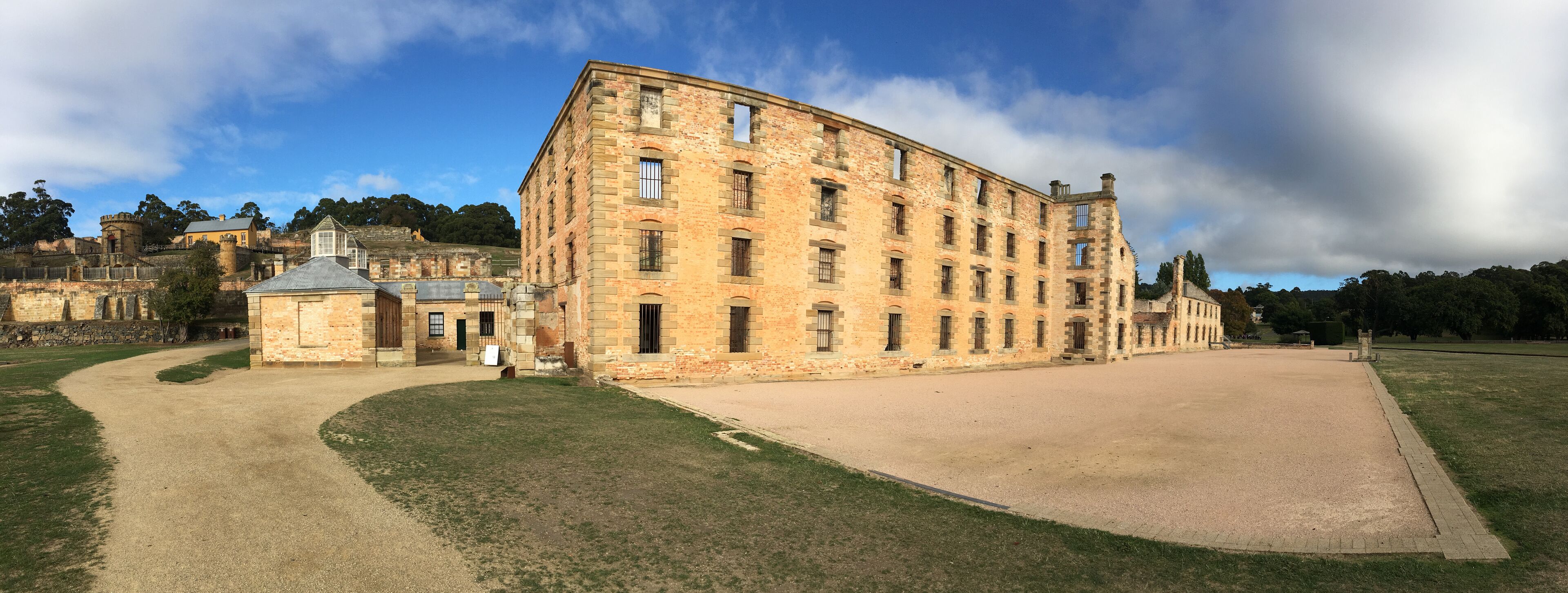 A historic stone building with a large courtyard, surrounded by a park and other historic structures.