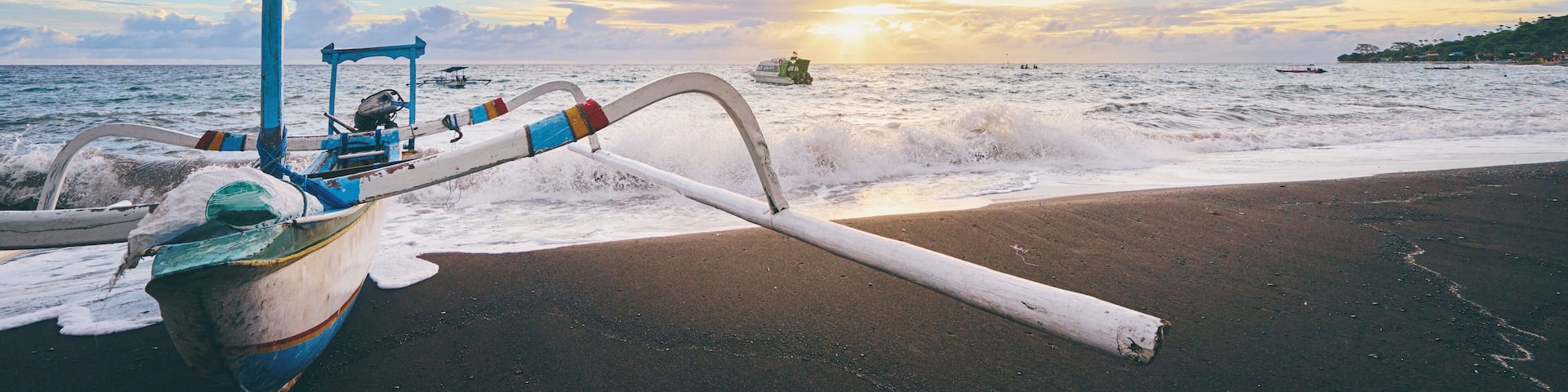 Beautiful sunrise. Ocean, beach and indonesian fishing boats.
