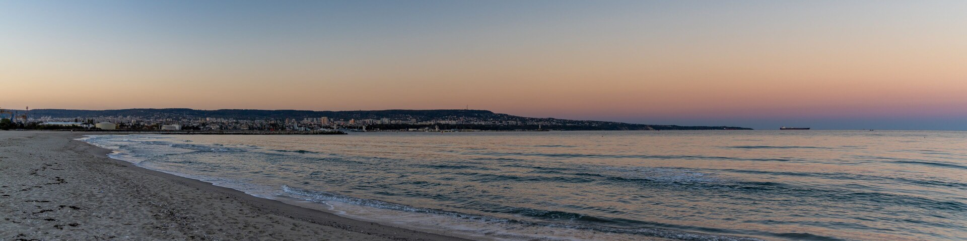 panorama landscape of Asparuhovo Beach at sunset and the Bulgarian Black Sea city of Varna in the background