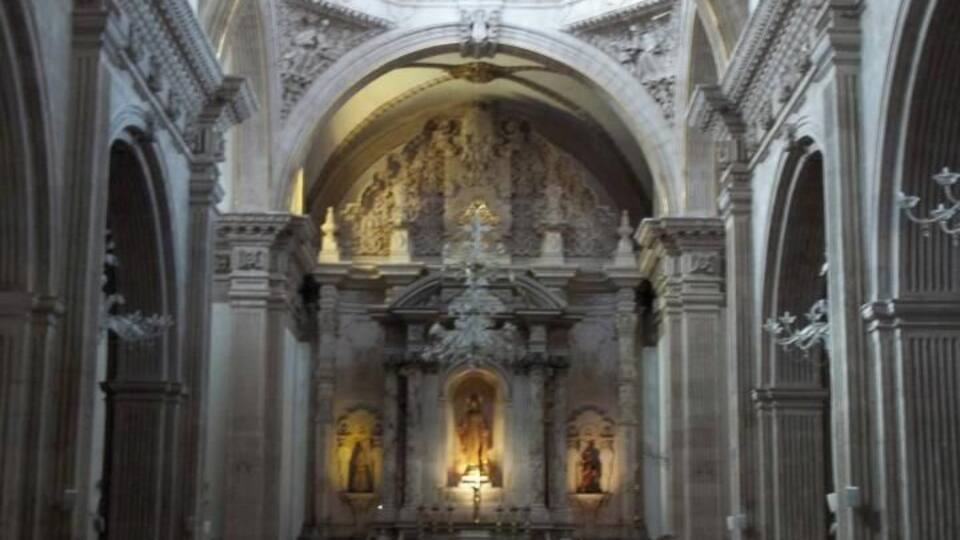 L’intérieur d’une église, avec ses rangées de bancs, son plafond voûté et ses statues religieuses richement décorées.