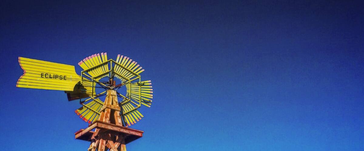 A windmill with a sign that reads "Eclipse" and a fence with "ROOSEVELT COUNTY FAIRGROUNDS" written on it.