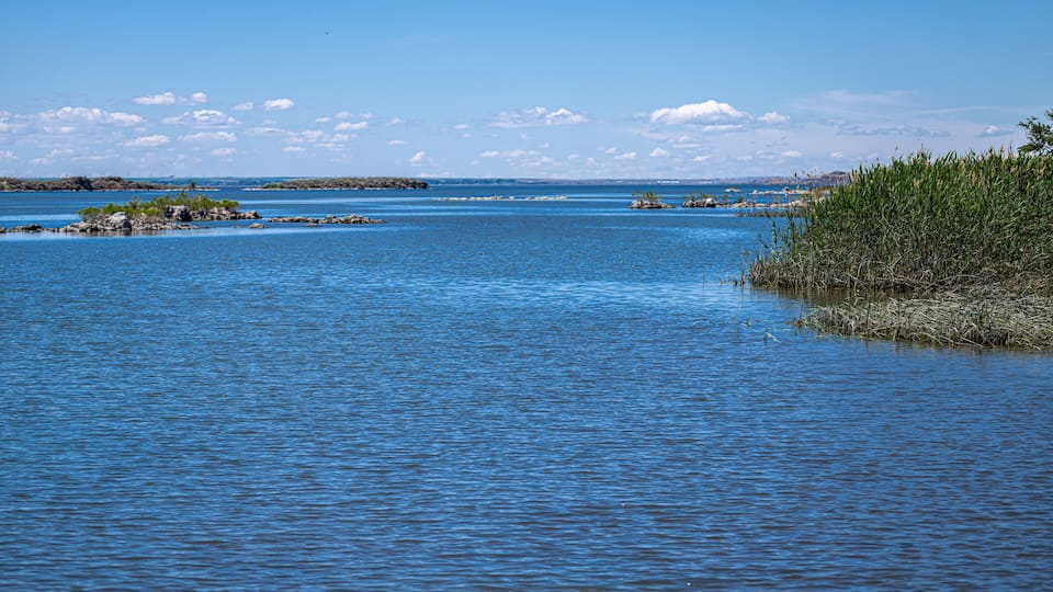 A calm body of water with clear blue skies and distant landforms.