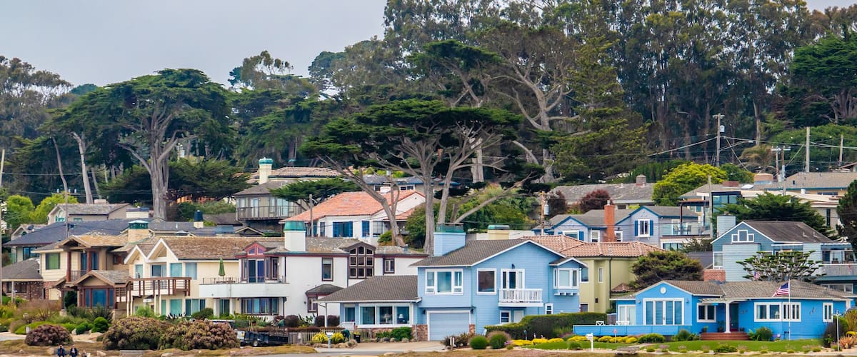 Houses in Pacific Grove, California (in Monterey County) overlook the rocky coastline, as viewed from a passing boat.