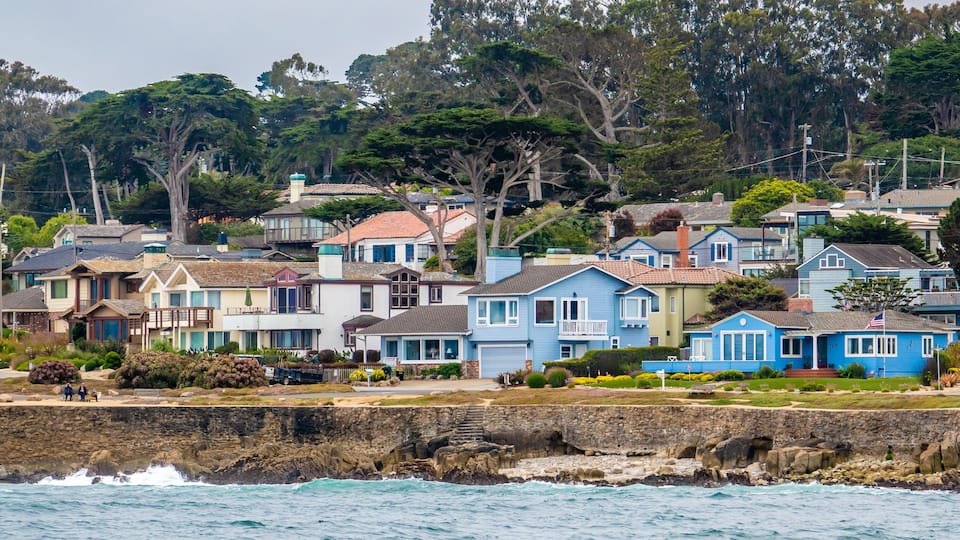 Houses in Pacific Grove, California (in Monterey County) overlook the rocky coastline, as viewed from a passing boat.