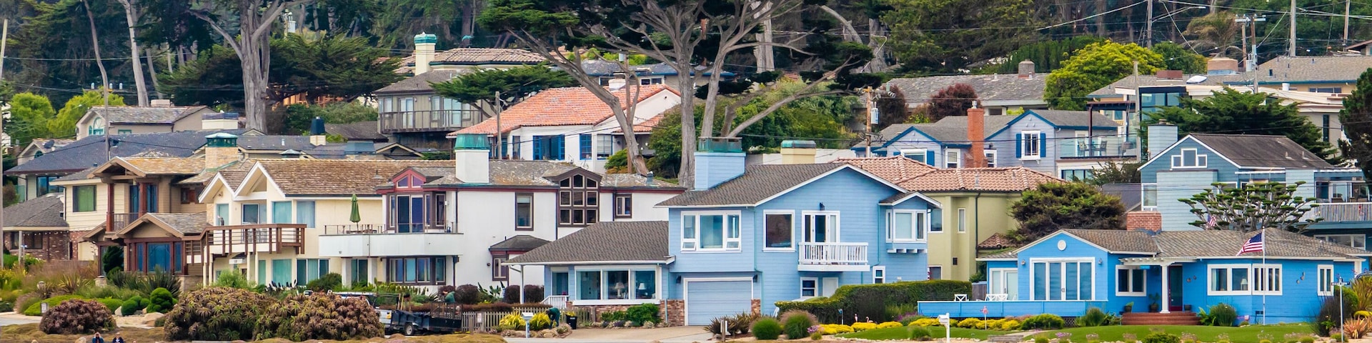 Houses in Pacific Grove, California (in Monterey County) overlook the rocky coastline, as viewed from a passing boat.