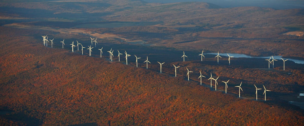 A landscape with a line of wind turbines on a hill.