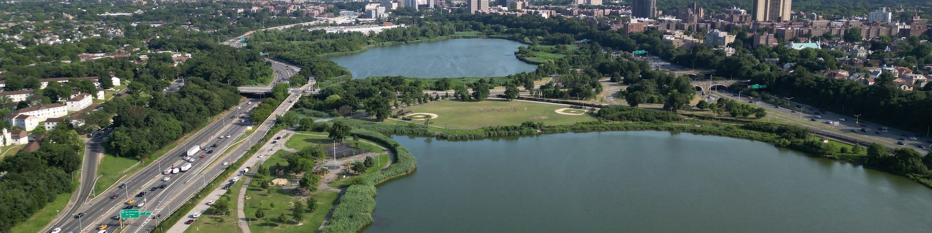 aerial view of new york city skyline from corona flushing meadows park with dramatic dark sky coming clouds at sunset (lake distant skyscrapers of manhattan far away) horizon silhouette shadow queens