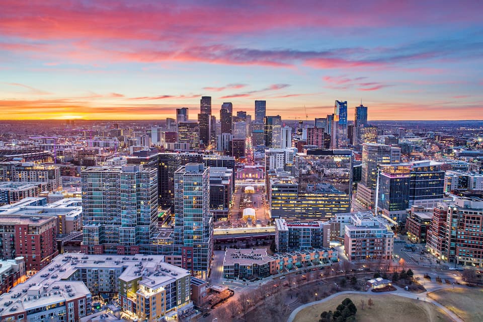 Paesaggio urbano al tramonto con moderni grattacieli e un insieme di edifici commerciali e residenziali.