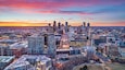 Un paisaje urbano al atardecer con modernos rascacielos y una combinación de edificios comerciales y residenciales.