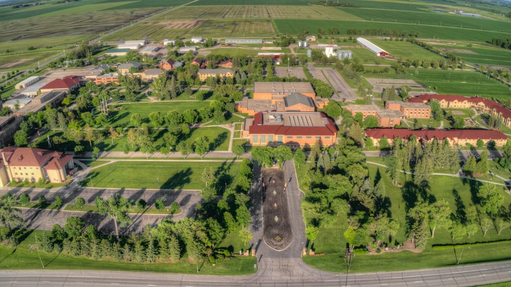 An aerial view of a campus with buildings, roads, and surrounding fields.
