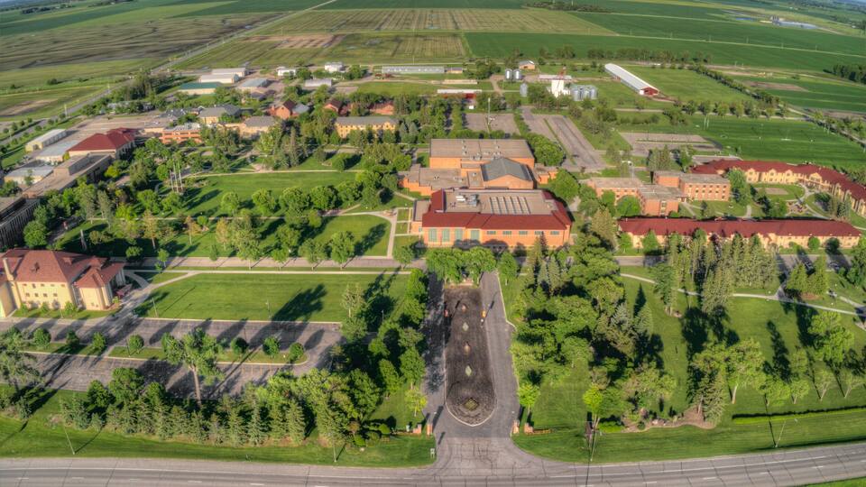 An aerial view of a campus with buildings, roads, and surrounding fields.