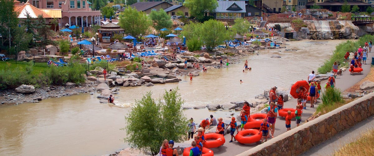 A riverside town with a river, people in water, and inflatable tubes.