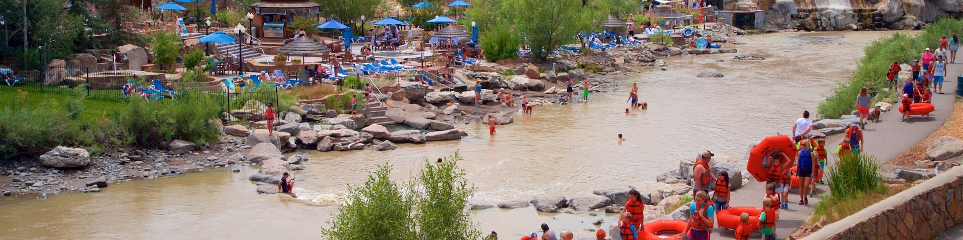 A riverside town with a river, people in water, and inflatable tubes.