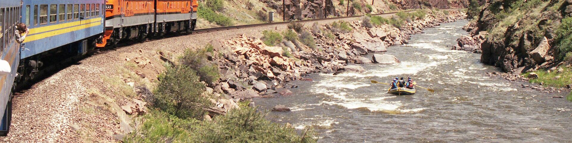 A train on a mountain track next to a river.
