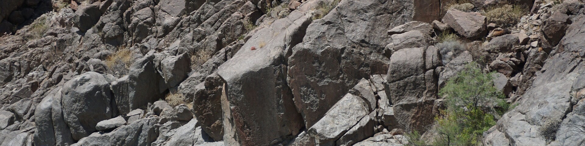Un río estrecho con grandes rocas y un risco rocoso al fondo.