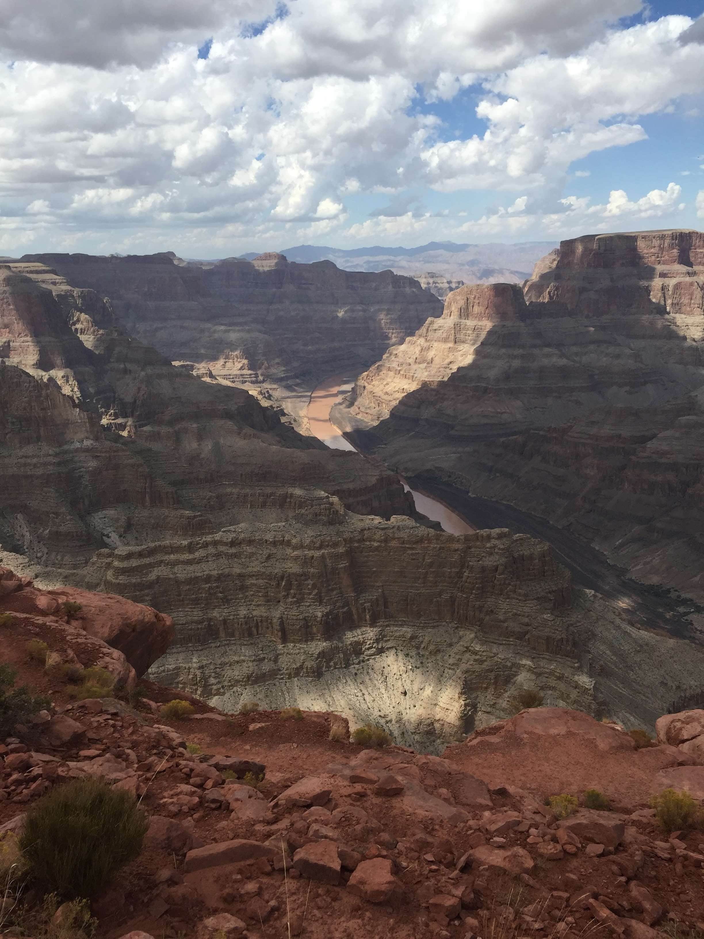 A canyon with layered rock formations and a river running through it.