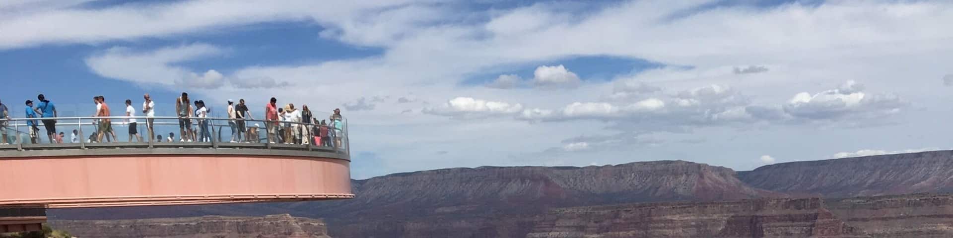 A canyon with layered rock formations and a viewing platform with people.
