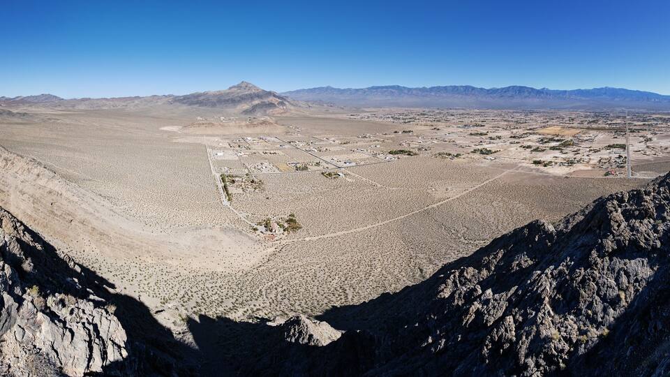 A mountainous landscape with a valley, rocky terrain, and distant mountains.