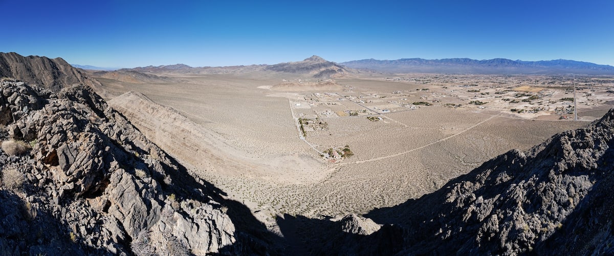 A mountainous landscape with a valley, rocky terrain, and distant mountains.