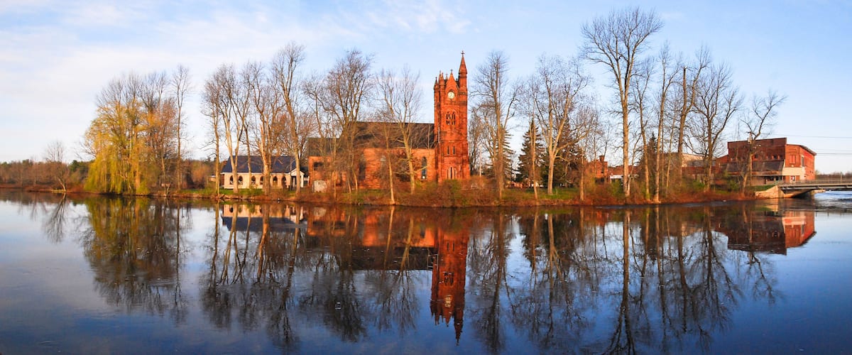 A historic church with a tall tower and a reflection in the water.