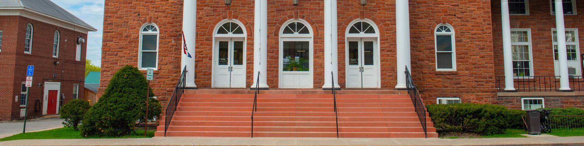 A brick building with a white pediment and columns labeled 'POTSDAM LIBRARY.'