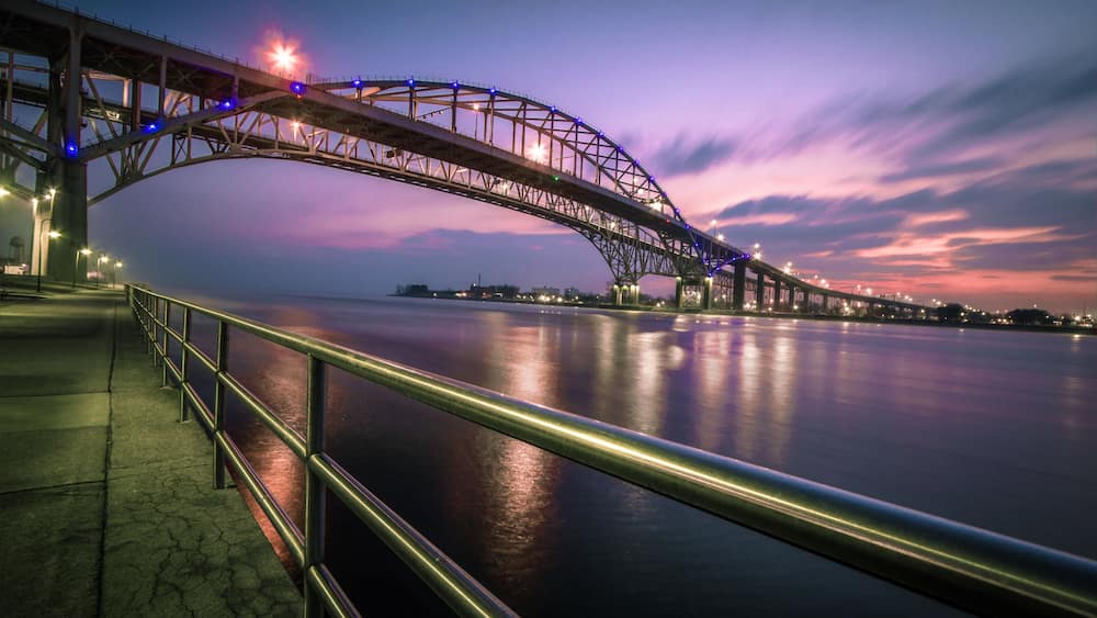 A bridge at twilight with lights reflecting on the water.