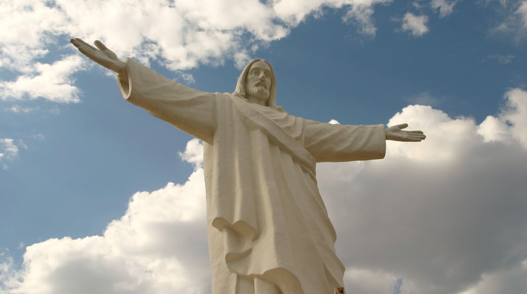 Statue of Christ the Redeemer stands majestically against the clouds in Cusco, Peru during a sunny afternoon