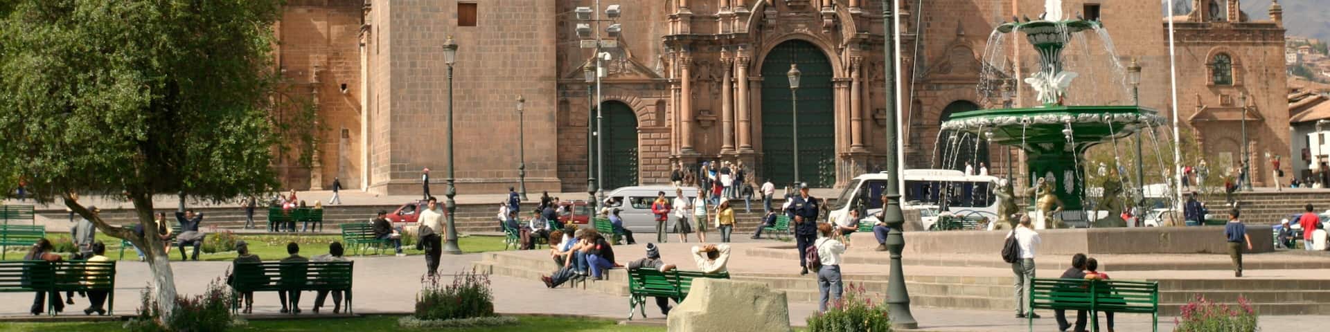 Cusco's historic plaza bustling with visitors and featuring the majestic cathedral and vibrant flag