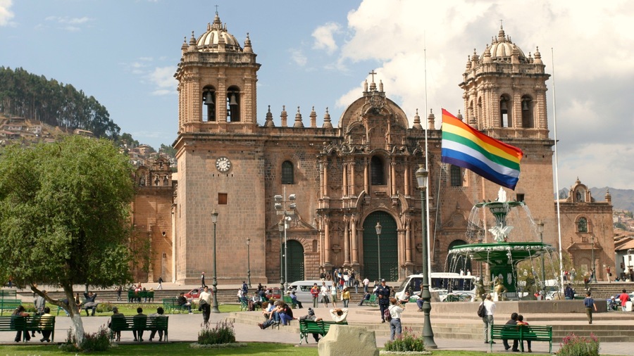 Cusco's historic plaza bustling with visitors and featuring the majestic cathedral and vibrant flag