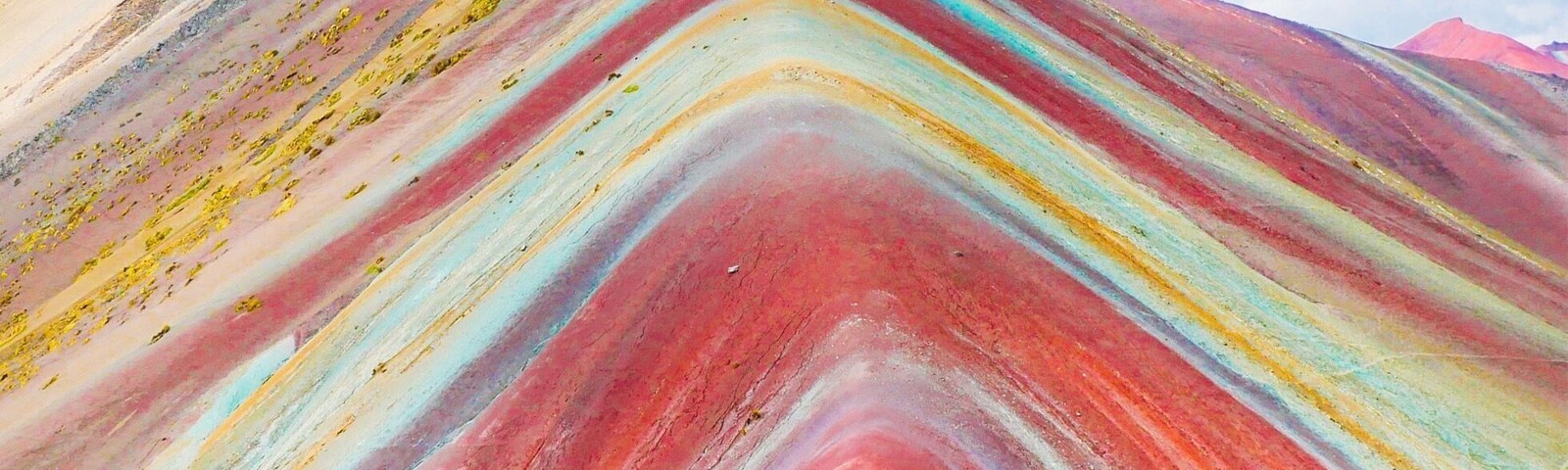 Una montaña colorida con capas horizontales marcadas de rojo, amarillo y azul.