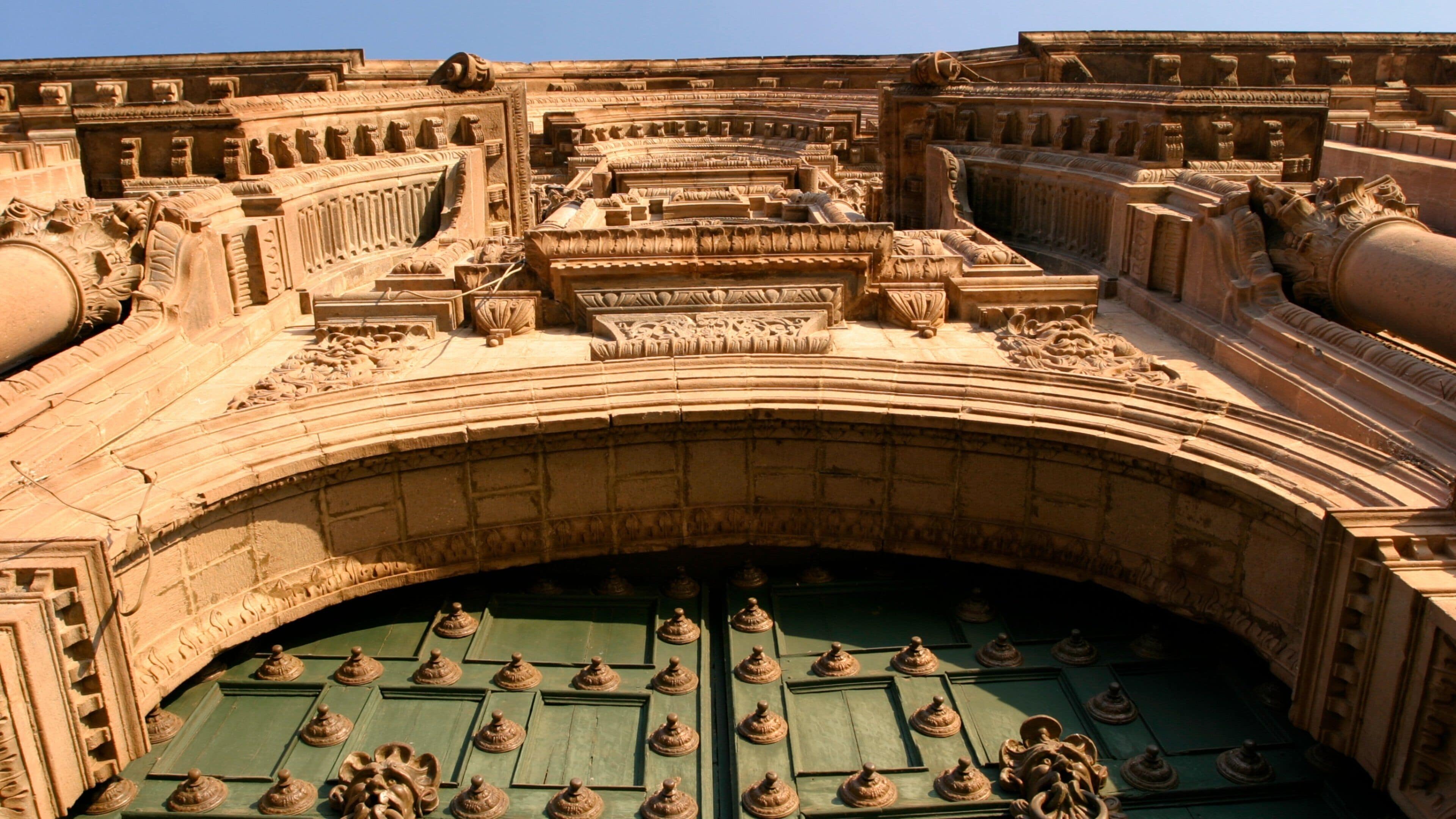 Historic architecture of Cusco showcasing intricate details and sturdy wooden doors under a clear blue sky