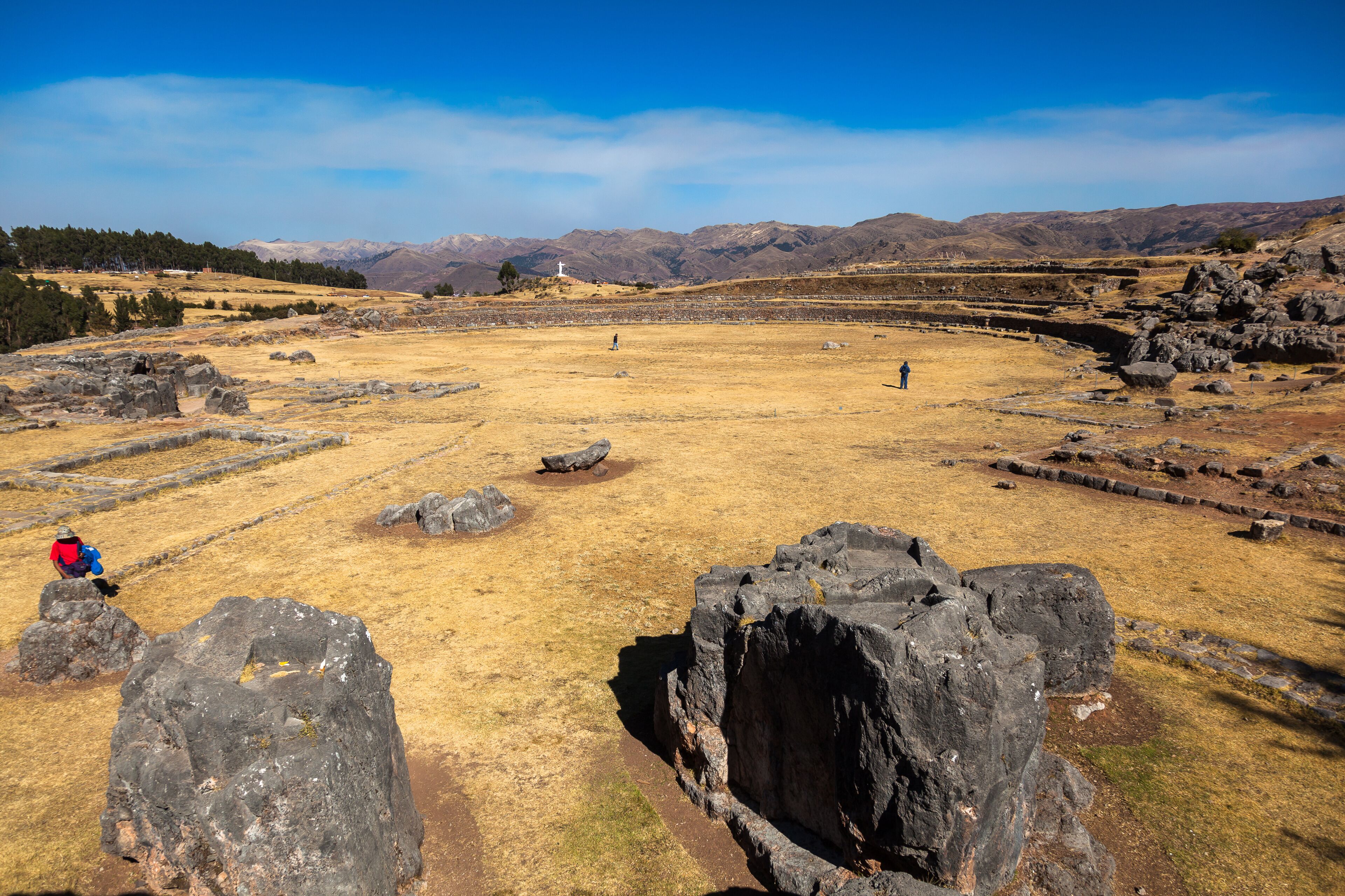Un sitio histórico con ruinas, un extenso campo abierto y montañas al fondo.