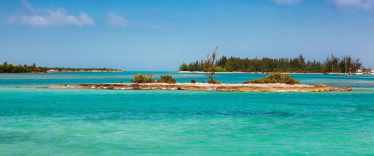 Turquoise waters, a sandy beach, and a forested island.