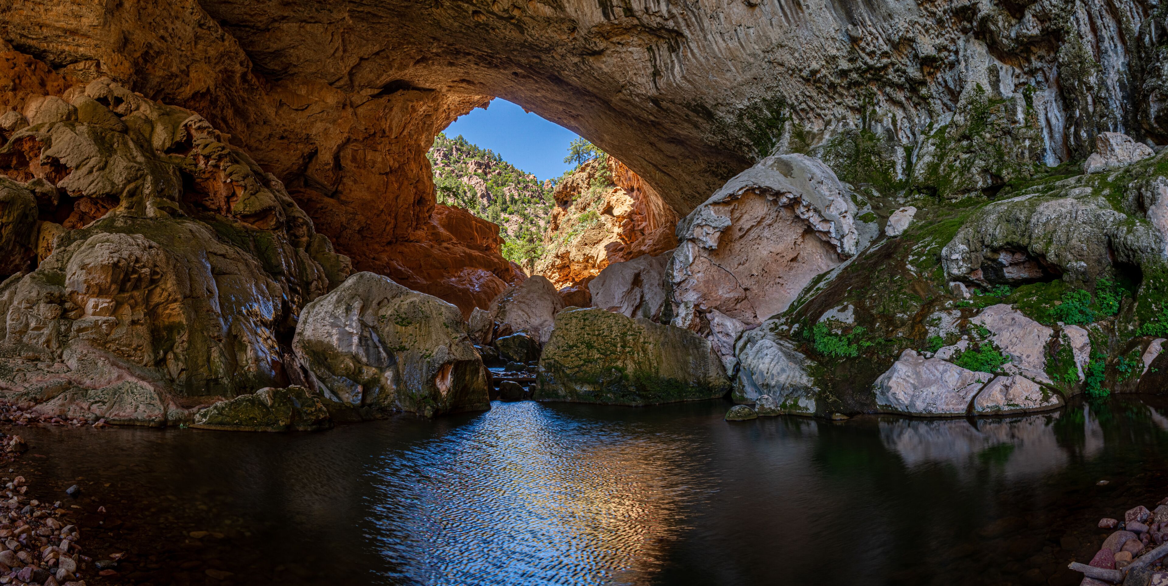 Inside Tonto Natural Bridge in the mountains of Arizona looking at the pond inside of the bridge.