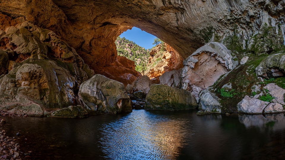 Inside Tonto Natural Bridge in the mountains of Arizona looking at the pond inside of the bridge.