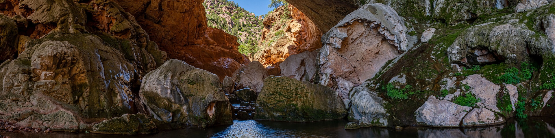 Entrada natural a una cueva con un arroyo que la atraviesa.