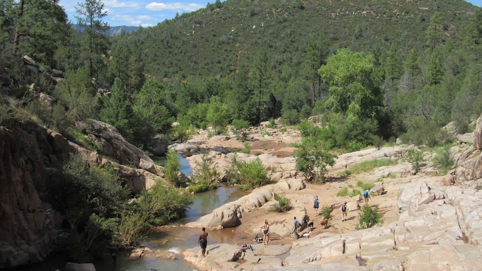 View over the Ellison Creek waterfall with unrecognizable tourists and locals below on the Water Wheel Falls hiking trail in Payson, Arizona