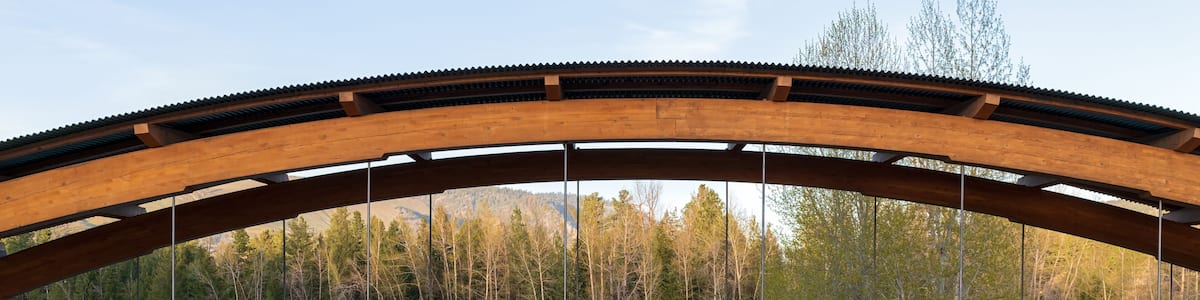 A wooden bridge over a river with a forested hillside in the background.