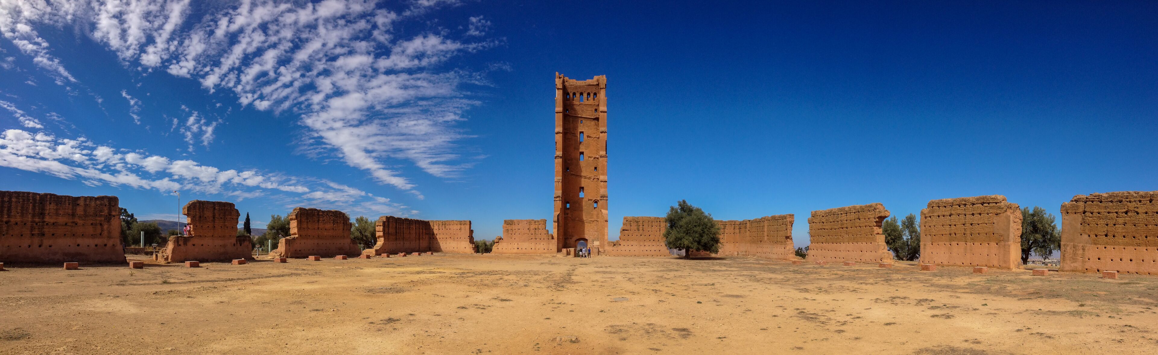 Ancient ruins with a tall tower and multiple brick structures.