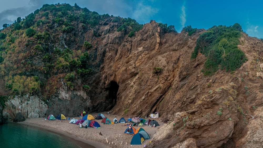 A rocky coastline with tents set up along the shore.