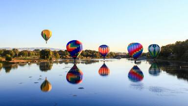 Dawn ascent of vibrant balloons over water
